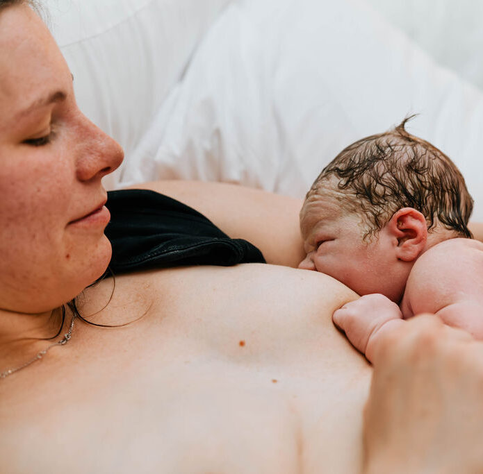 a mother breastfeeding her newborn in bed